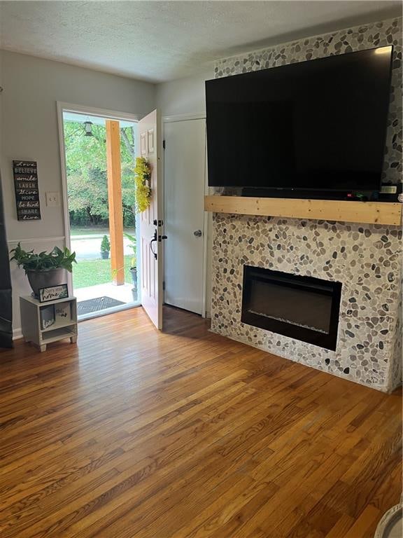 unfurnished living room with a textured ceiling, a tile fireplace, and hardwood / wood-style floors