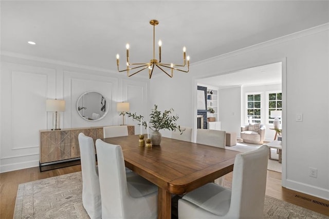 5143 Meadowlake Ln, Dunwoody, GA 30338 - dining area featuring a chandelier, crown molding, wood finished floors, built in features, and baseboards