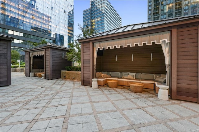 view of patio featuring an outdoor hangout area, an outbuilding, and a city view