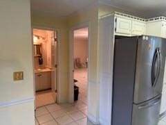 kitchen featuring white cabinets, stainless steel refrigerator, and light tile patterned floors