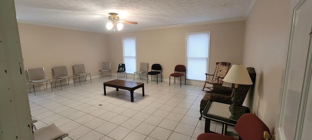 living room with a textured ceiling, ceiling fan, light tile patterned floors, and crown molding