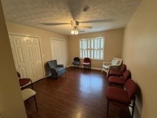 sitting room featuring dark wood-type flooring, a textured ceiling, and ceiling fan