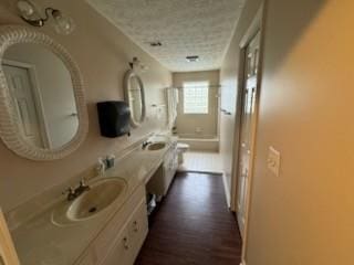 bathroom featuring a textured ceiling, toilet, vanity, and wood-type flooring