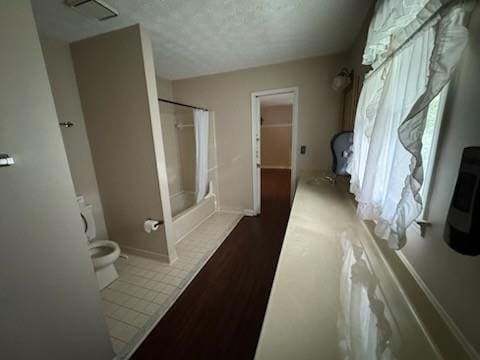 bathroom with a textured ceiling, tile patterned floors, and toilet