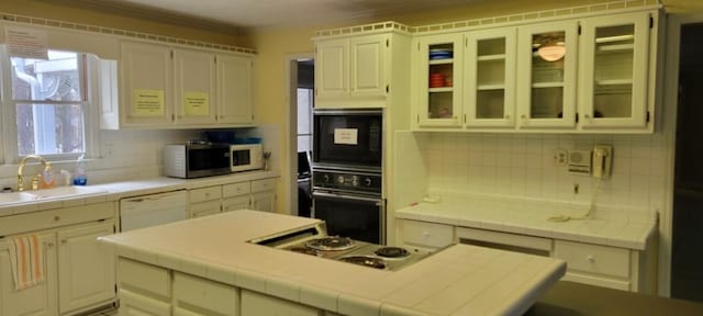 kitchen featuring sink, tile counters, decorative backsplash, and white appliances