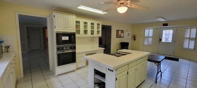 kitchen with tile countertops, a kitchen island, light tile patterned flooring, and black appliances