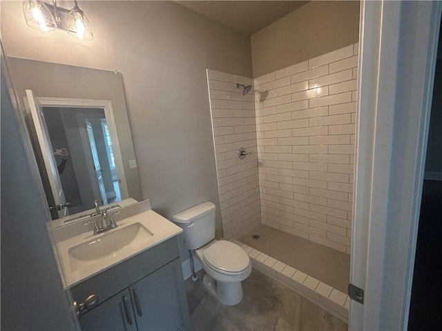 bathroom with tile patterned flooring, vanity, toilet, and tiled shower