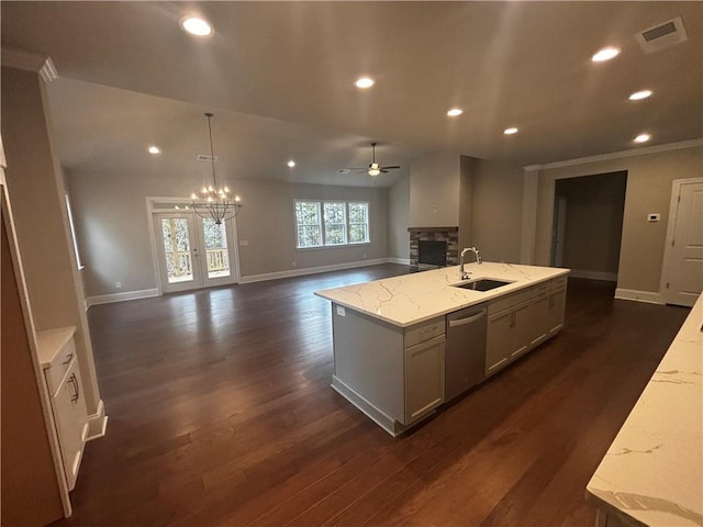 kitchen featuring light stone counters, a center island with sink, dark hardwood / wood-style floors, sink, and stainless steel dishwasher