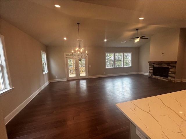 unfurnished living room featuring a fireplace, dark hardwood / wood-style flooring, vaulted ceiling, and ceiling fan with notable chandelier