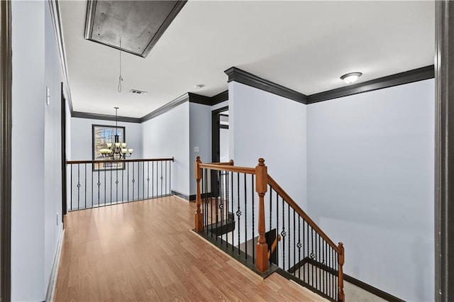 hall featuring crown molding, visible vents, attic access, an upstairs landing, and wood finished floors