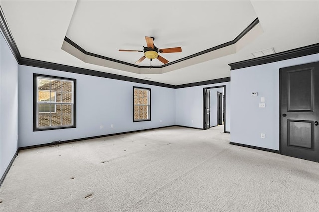 empty room featuring ornamental molding, a raised ceiling, carpet flooring, and baseboards