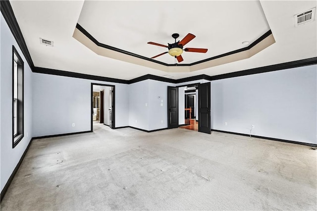 empty room with ornamental molding, a raised ceiling, and visible vents