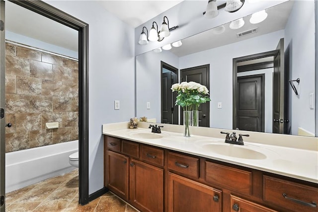 full bath with toilet, double vanity, a sink, and visible vents