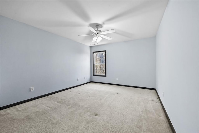 carpeted spare room featuring a ceiling fan and baseboards