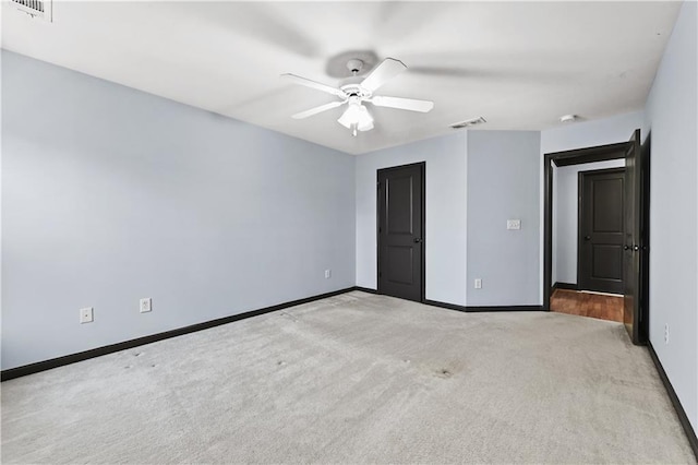 carpeted spare room with a ceiling fan, visible vents, and baseboards