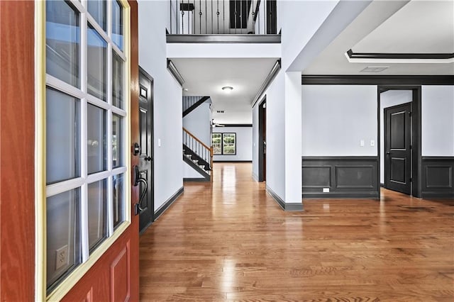 entrance foyer featuring visible vents, wainscoting, stairway, and wood finished floors