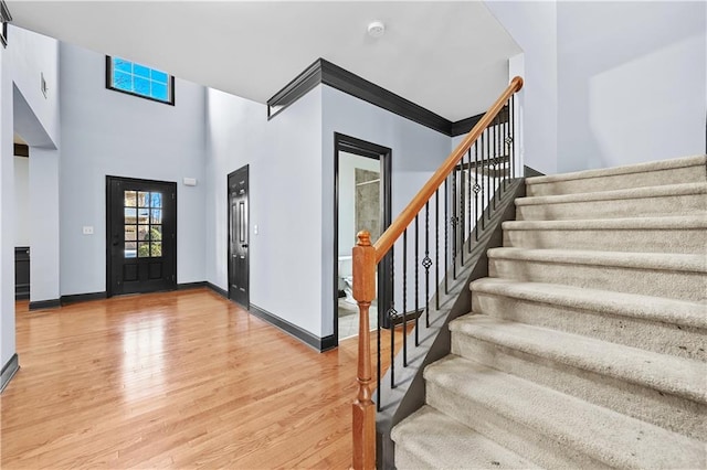 entrance foyer featuring light wood-type flooring, a high ceiling, stairway, and baseboards