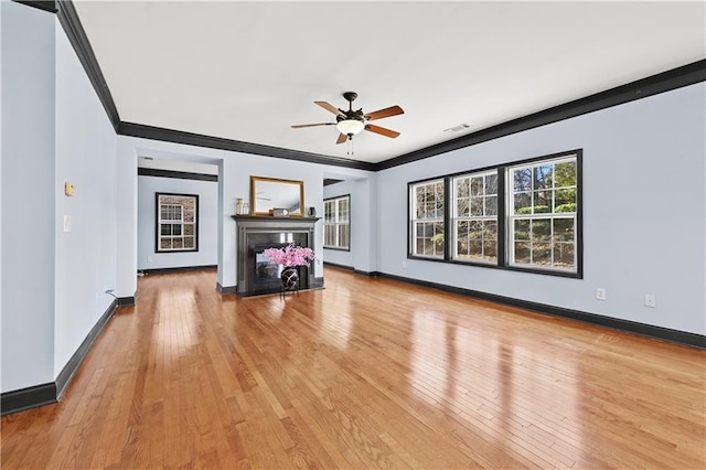 unfurnished living room with light wood-type flooring, ornamental molding, a fireplace, and visible vents