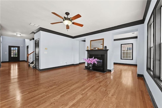 living area with hardwood / wood-style flooring, baseboards, stairway, and a glass covered fireplace