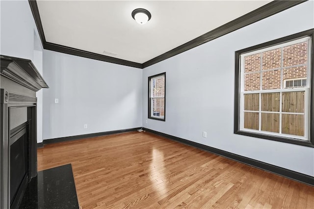 unfurnished living room featuring baseboards, wood finished floors, and crown molding