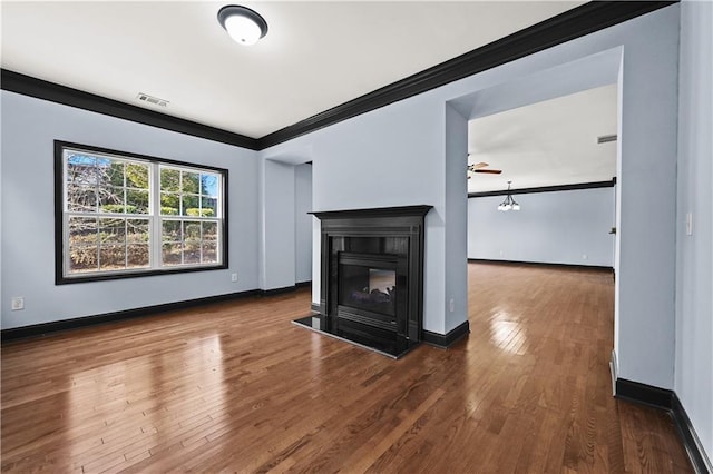 unfurnished living room with visible vents, baseboards, wood-type flooring, crown molding, and a multi sided fireplace