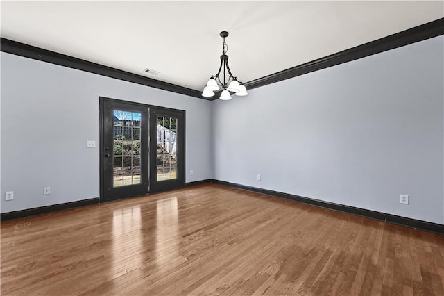 unfurnished room with visible vents, a notable chandelier, baseboards, and wood finished floors