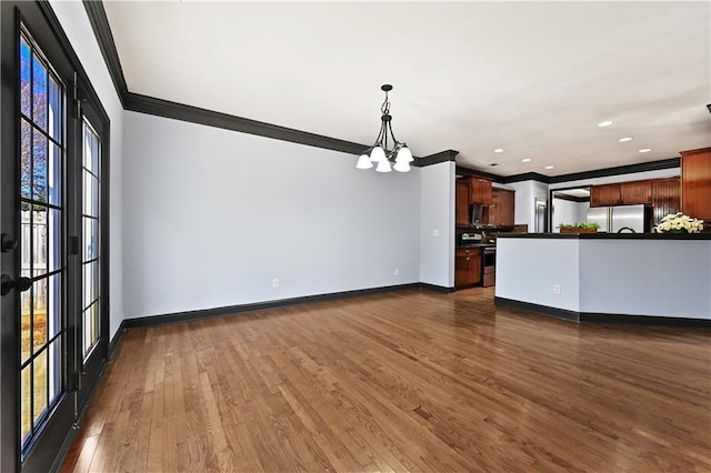 unfurnished living room with recessed lighting, an inviting chandelier, dark wood-type flooring, ornamental molding, and baseboards