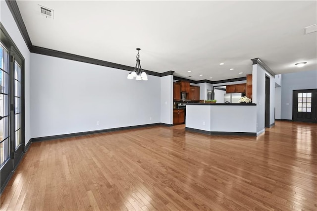 unfurnished living room featuring ornamental molding, visible vents, dark wood finished floors, and a notable chandelier