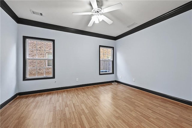 spare room featuring light wood-style flooring, visible vents, baseboards, and ornamental molding