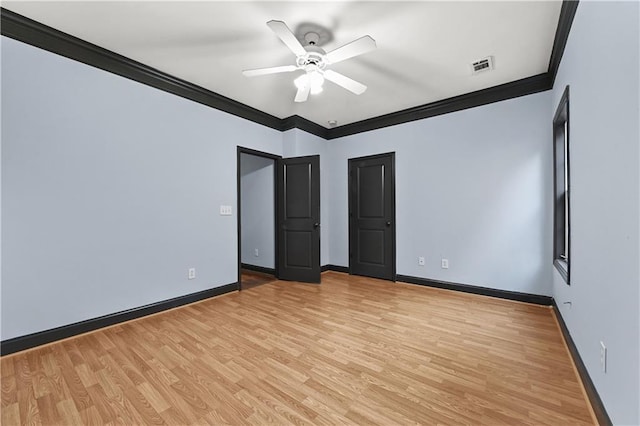 spare room featuring light wood finished floors, ornamental molding, visible vents, and baseboards