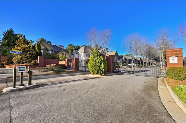 view of street with curbs, a gated entry, a residential view, and a gate