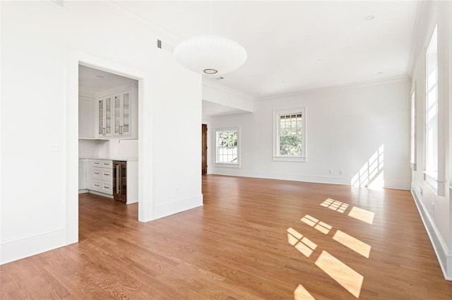 1585 S Ponce De Leon Ave NE Unit 20, Atlanta, GA 30307 - unfurnished living room featuring crown molding, a dry bar, baseboards, light wood-style floors, and wine cooler