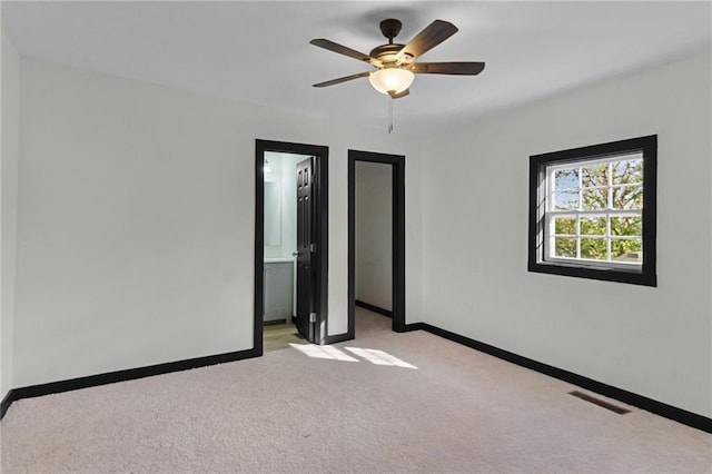 unfurnished bedroom with ceiling fan, light carpet, and connected bathroom