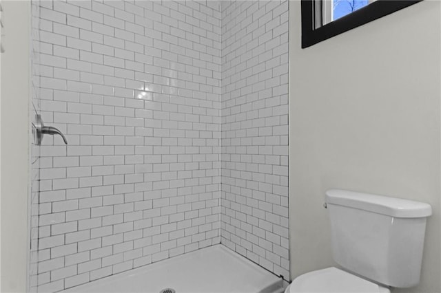 bathroom with toilet and a tile shower