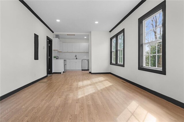 unfurnished living room with light hardwood / wood-style floors, crown molding, and sink