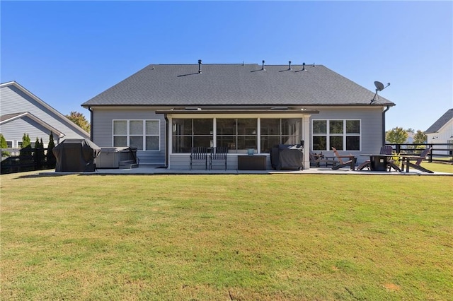 back of house with a sunroom, a hot tub, a patio area, and a lawn