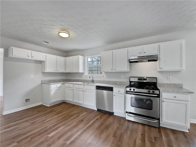 kitchen featuring light stone counters, dark wood-type flooring, white cabinetry, appliances with stainless steel finishes, and sink