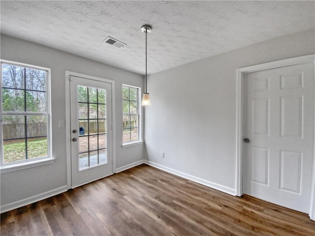 unfurnished dining area featuring dark hardwood / wood-style flooring and a textured ceiling