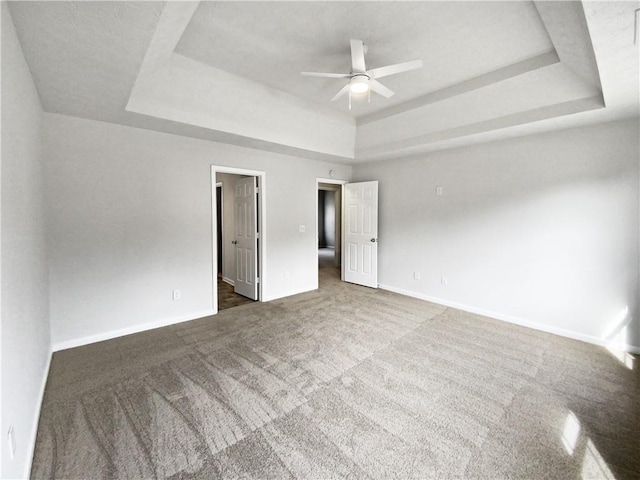 carpeted empty room featuring a raised ceiling and ceiling fan