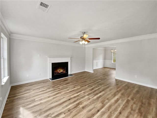 unfurnished living room featuring crown molding, ceiling fan with notable chandelier, and hardwood / wood-style flooring