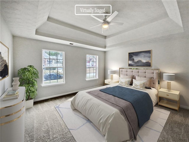 bedroom with a raised ceiling, light carpet, and ceiling fan