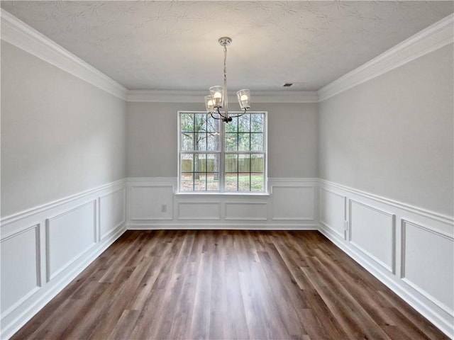 unfurnished room with a textured ceiling, dark hardwood / wood-style flooring, crown molding, and a chandelier