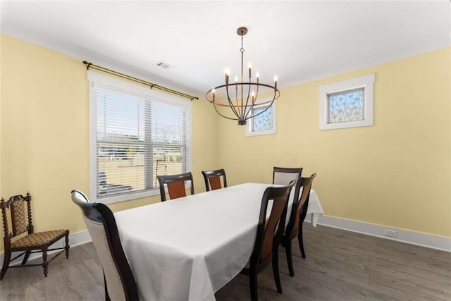 dining space with an inviting chandelier, wood finished floors, visible vents, and baseboards