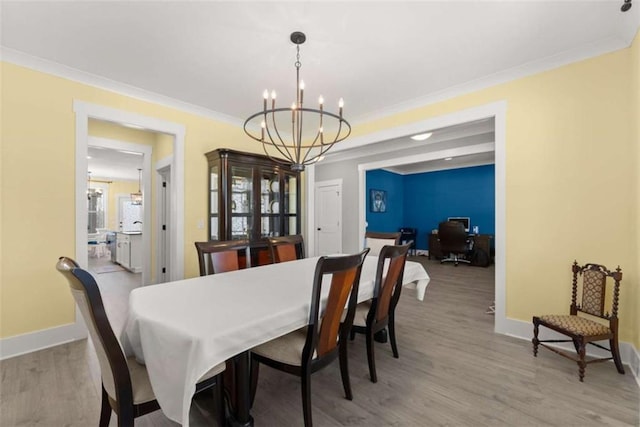 dining space featuring baseboards, ornamental molding, a chandelier, and wood finished floors