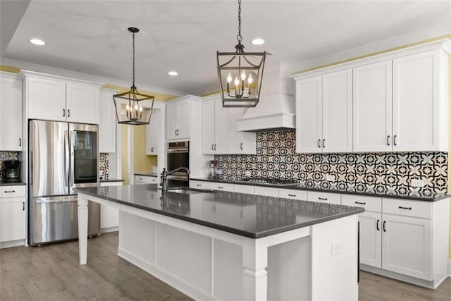 kitchen with tasteful backsplash, dark countertops, appliances with stainless steel finishes, a sink, and wood finished floors