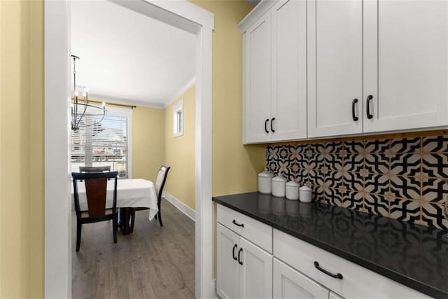 kitchen with dark countertops, white cabinetry, baseboards, and wood finished floors