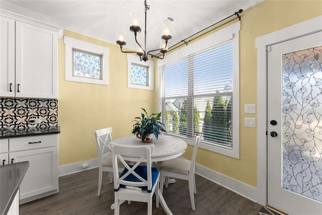 dining room featuring a chandelier, dark wood finished floors, and baseboards