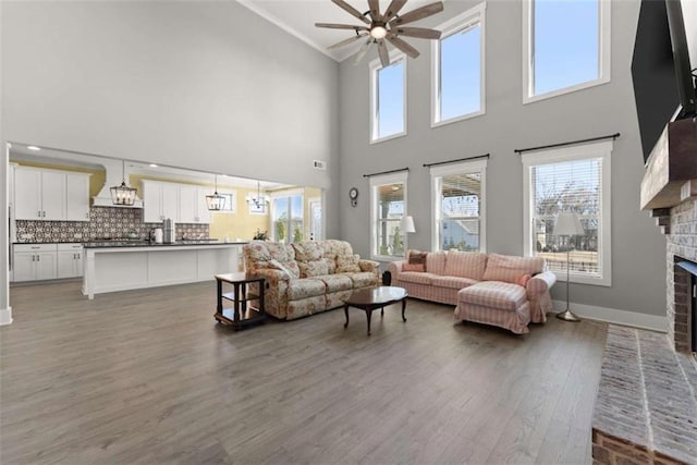 living room featuring a fireplace, visible vents, a ceiling fan, wood finished floors, and baseboards