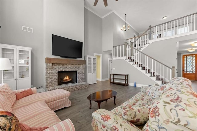 living room with a fireplace, crown molding, visible vents, wood finished floors, and stairs