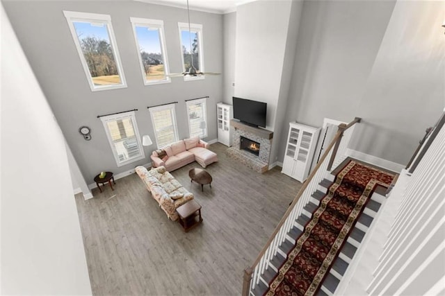 living room featuring a high ceiling, a fireplace, wood finished floors, and baseboards